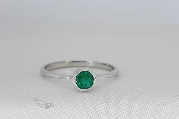 Anillo solitario con esmeralda
redonda al bisel
