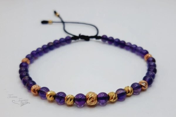 Pulsera tejida hilo negro con 32 bolitas amatistas y 4 bolitas diamantada oro rojo y 5 bolitas diamantadas de oro amarillo y 2 terminales oro amarillo